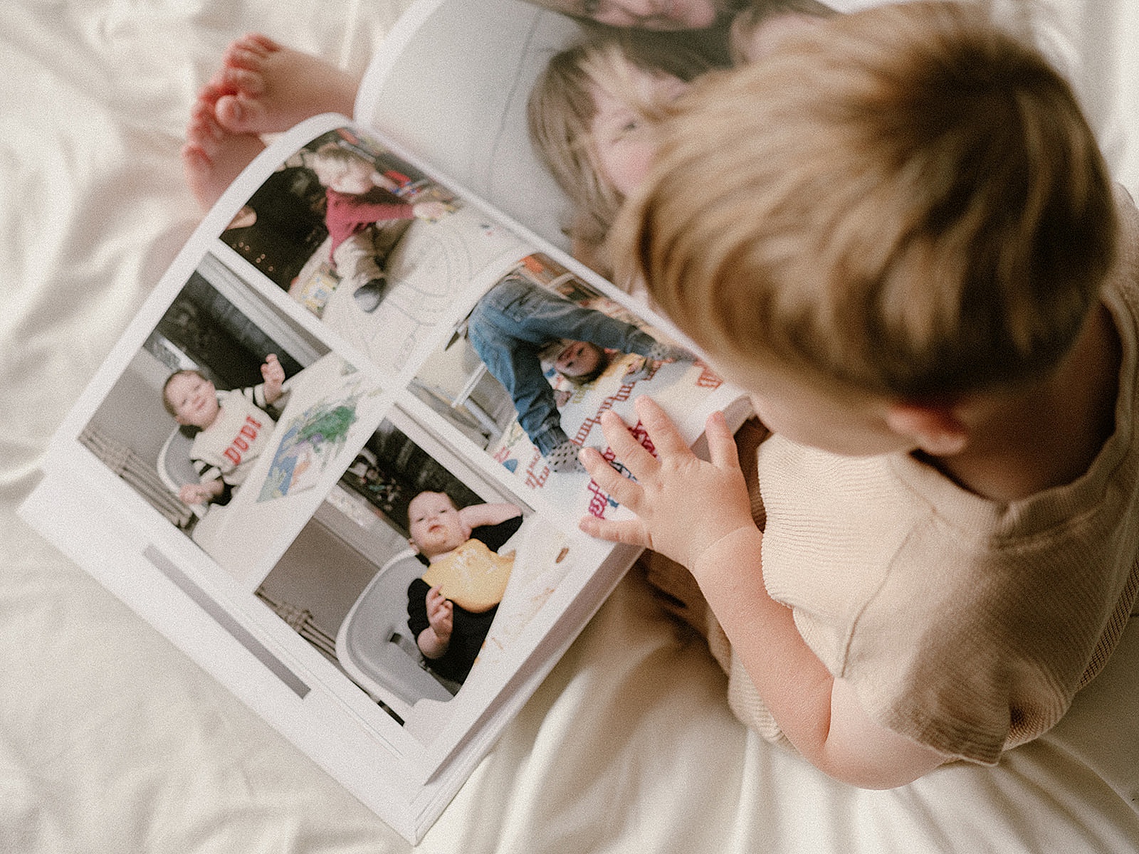 A little boy holds a custom baby book in his lap.