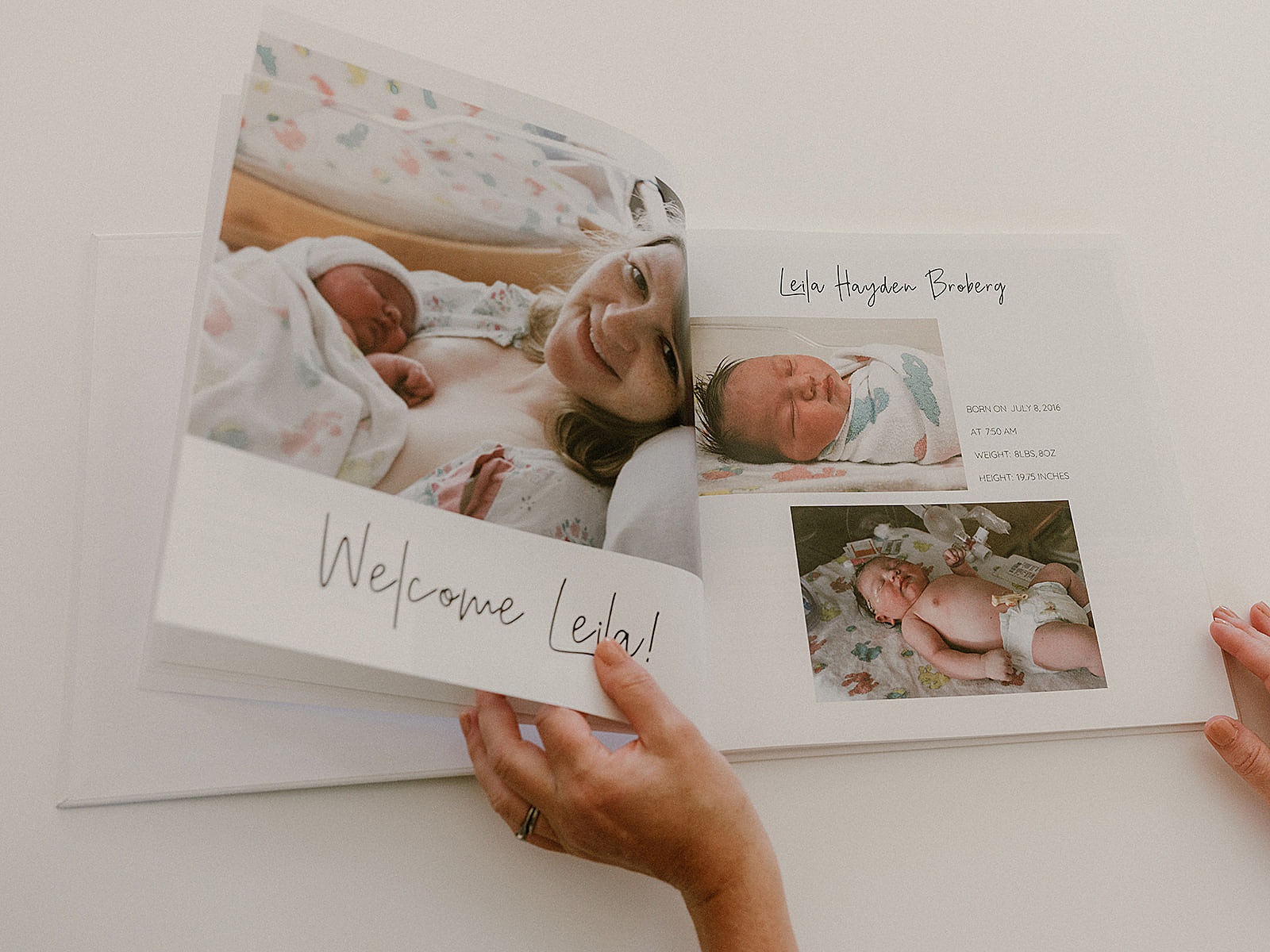 A mother opens a baby book to a newborn announcement.