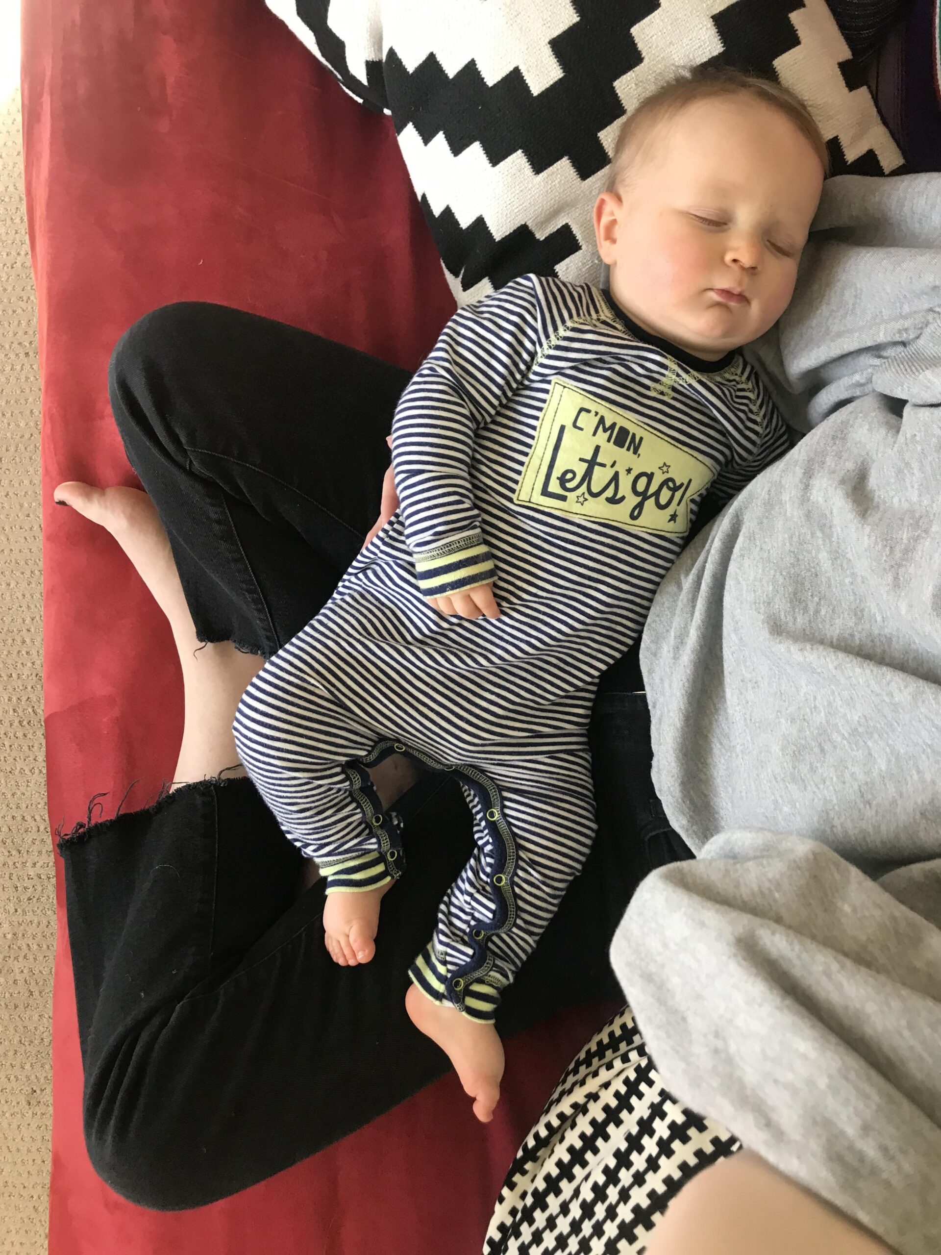 A baby sleeps in a mother's lap in a phone photo.