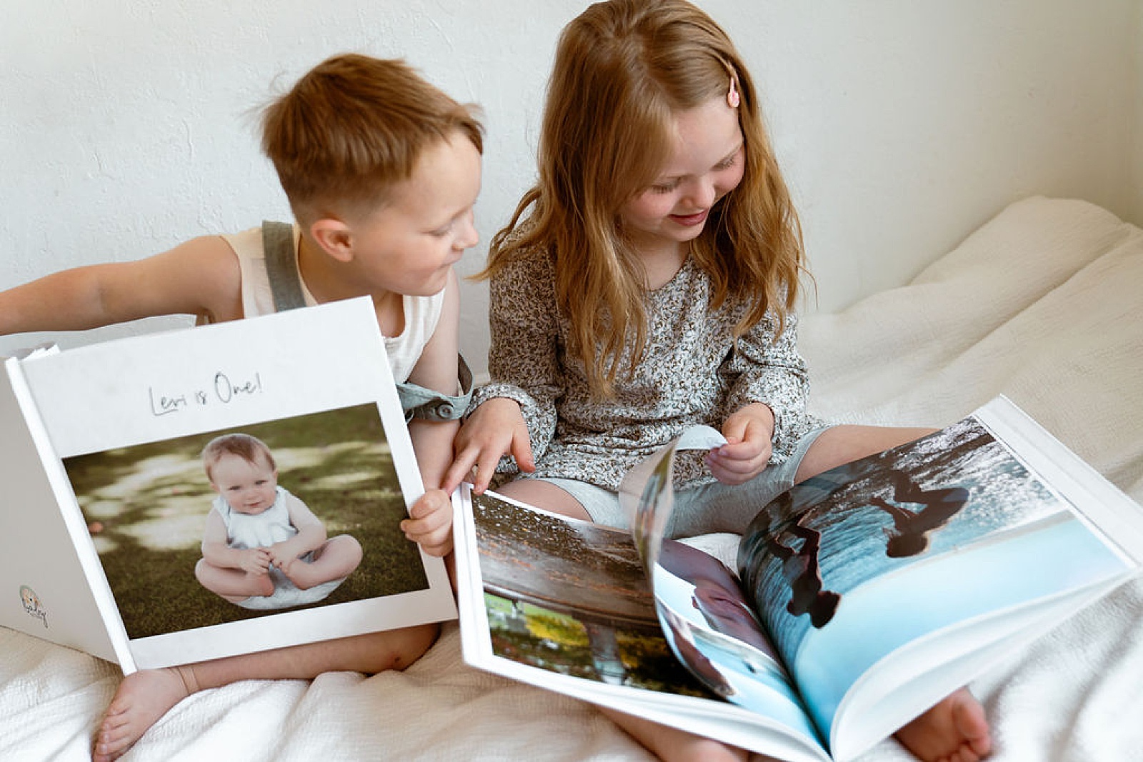 Two children show each other pages in their baby books.