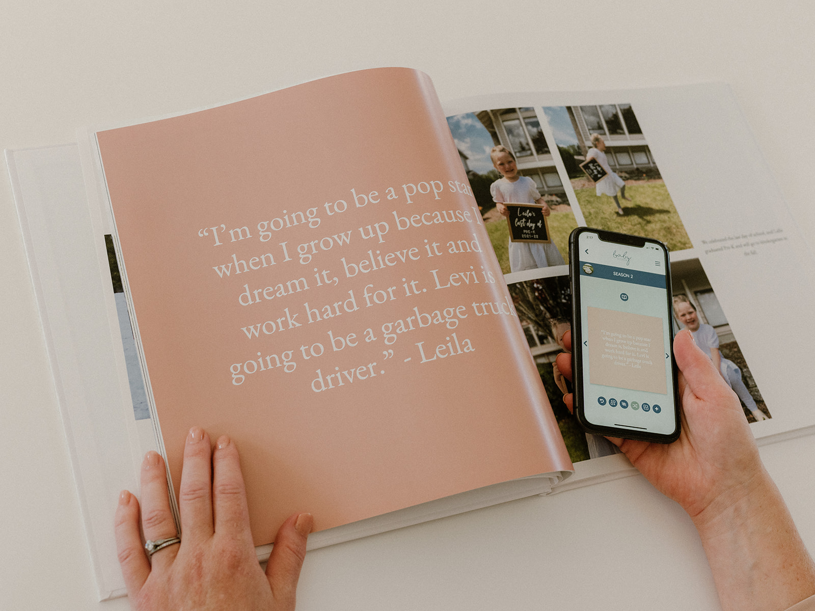 A woman holds a cell phone beside a custom memory book.