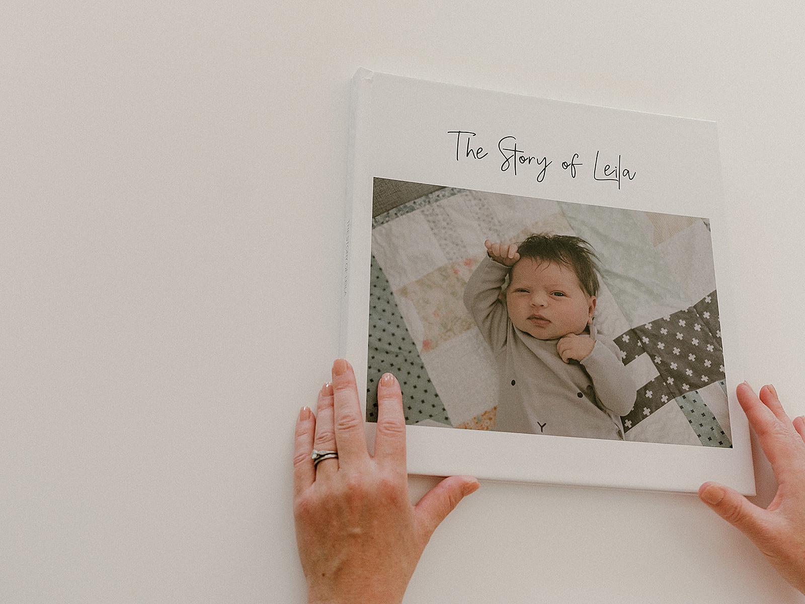 A woman opens a custom photo book for baby.