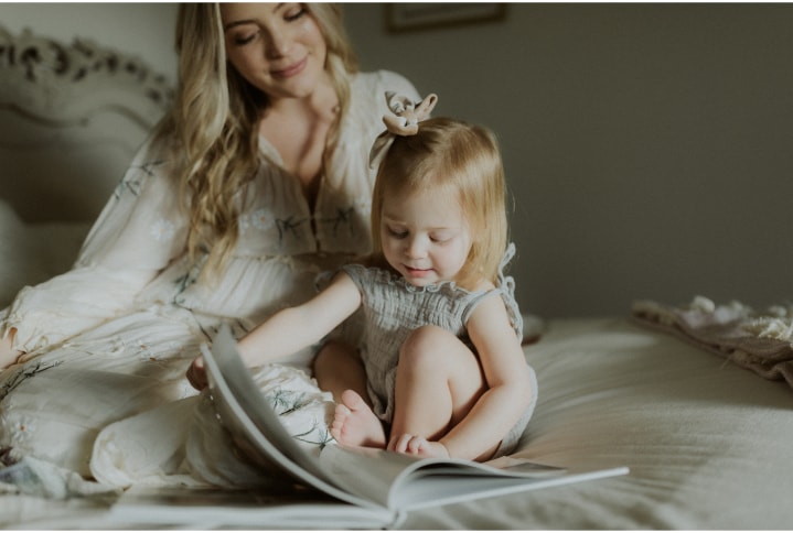Pregnant mom and toddler flipping through keepsake baby book